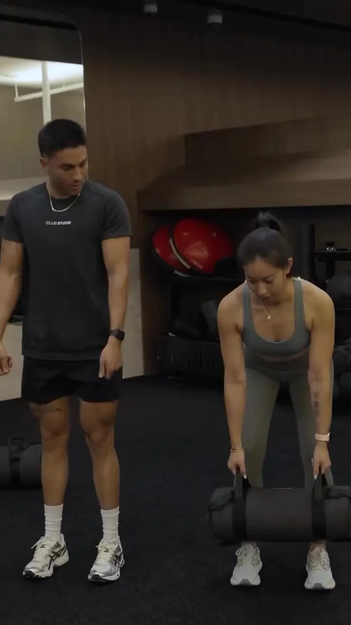 Coach Santi coaching a client setting up a sandbag deadlift during strength training in Costa Mesa