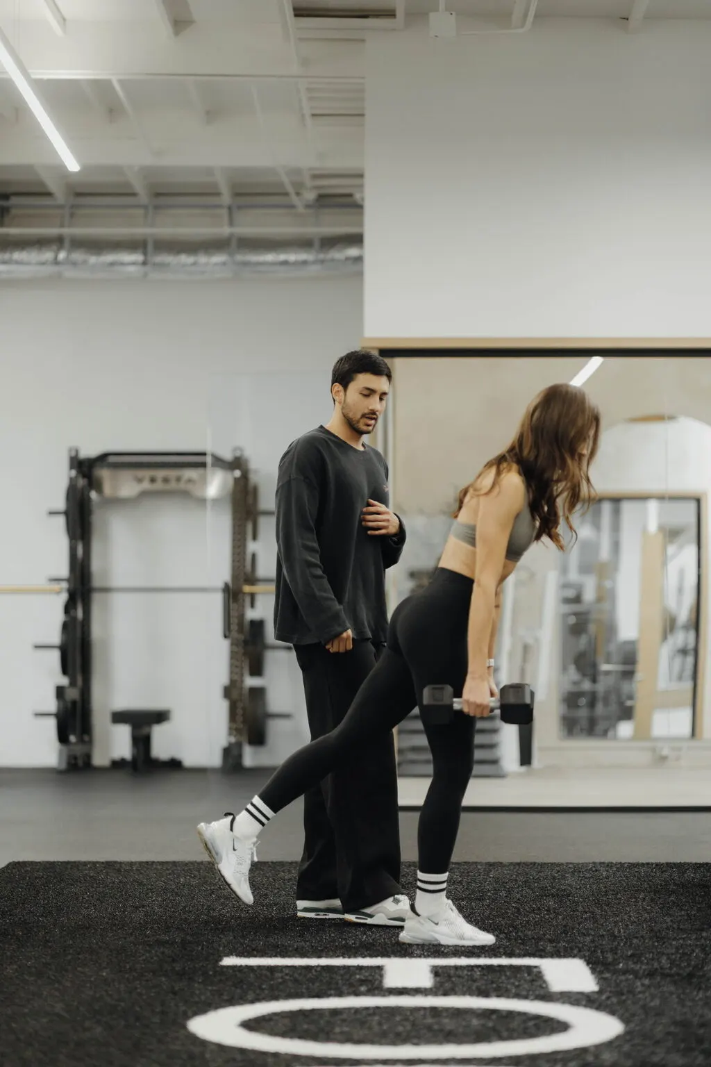 Coach Santi coaching a client through a split-stance hinge with a dumbbell at Focus Athletics in Costa Mesa, part of a complete, tailored weight loss program