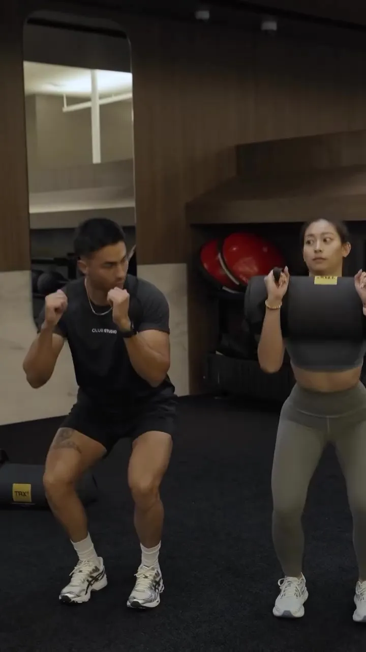 Coach Santi squatting alongside a Costa Mesa client during a fun, tailored weight loss session at Focus Athletics